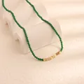 Dettaglio della collana di perle verdi retrò con barre dorate su supporto bianco - Diaspro Pezzi d'Oro