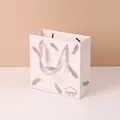Elegant minimalist white paper gift bag with silver leaf pattern and grey ribbon handles - Feather Print / Large (20x20x8cm)