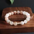Nahaufnahme eines Super Seven Naturkristall Armbands mit eleganten vergoldeten Details - Wespentaille Transferring / 10mm
