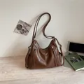 Stylish brown leather hobo bag with zipper details on a desk with a laptop and book. - 29*11*17 / Caramel color