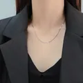 Detailed view of a minimalist silver snake chain necklace worn with a black blazer - Snake Chain Style