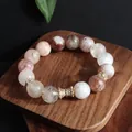 Detailaufnahme eines Super Seven Kristallarmbands mit goldenen Verzierungen. - Wespentaille Transferring / 12mm