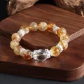 Detailed view of a natural citrine bead bracelet with silver spacers on a wooden stand. - Yellow Tower Crystal Style