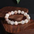 Nahaufnahme eines Super Seven Kristall-Armbands mit einem goldfarbenen Zirkonia-Element - Zylinder Besetzt / 10mm