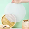 Gros plan d'un tapis de cuisson en silicone blanc tenu au-dessus d'un cuiseur en bambou - Maillage Rond (D0051) / 1 Pièce