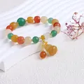 Nahaufnahme eines Goldseiden-Jade-Armbands im ethnischen Stil mit gelbem Kürbis-Anhänger - Gelbgrüne Tonnenperle Mit Flaschenkürbis