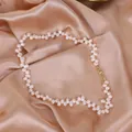Close-up of a natural white rice pearl necklace on an elegant champagne satin fabric background - White Necklace
