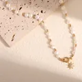 Dettaglio di una collana di perle naturali d'acqua dolce con ciondolo a sole dorato e pavé. - Stile 9