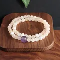 Detailopname van dubbelstrengs kristallen armband met parels en amethist op een houten dienblad. - Dubbele Wikkelarmband / Topaas