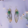 Detailansicht grüner Schmetterlingsflügel-Ohrringe mit Glitzer und Strass für Bräute - Farbverlauf Grün-Gold-Strass
