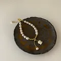 Detail showing freshwater pearls and a delicate shell flower charm on a ceramic plate. - Freshwater Pearl Bracelet (Gold Plated)