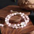 Detailed macro shot of a rose quartz double-strand bracelet on a natural wood display - Pink Crystal