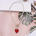 Primo piano di una collana di perle barocche naturali con un vivace ciondolo a cuore rosso rubino - cuore rosso