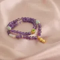 Close-up of double-strand purple amethyst bracelet with golden peanut charm on pink silk. - Peanut Pendant Style (TA-BR-492) / Purple Multicolor