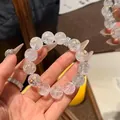 Nahaufnahme eines klaren Quarzperlenarmbands mit einem glitzernden Silberanhänger - Burst White Crystal Bracelet / Weiß