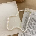 Detailed view of a vintage-style irregular rice pearl necklace on textured paper. - Minimalist Necklace / Natural Pearl Color