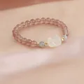 Macro detail view of a natural strawberry quartz bracelet featuring a white carved charm - Pet Carving Style
