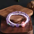 Close-up of a double-strand amethyst bracelet with a pink jade donut bead on wood. - Amethyst Double Loop Loop Bracelet