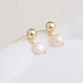 Dettaglio di eleganti orecchini a lobo dorati con pendenti in perle d'acqua dolce - Stile a Sfera / Orecchini a Bottone a Sfera Dorati