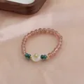 Close-up view of a natural strawberry quartz crystal beaded bracelet with elegant gold flower detail. - Hollow Flower