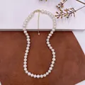 Close-up of an elegant natural pearl necklace with gold clasp on textured background. - Round Bead Necklace / Natural Pearl Color