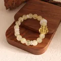 Detail view of yellow crystal bead bracelet featuring a carved fox charm on a wooden stand - Citrine With Accessories