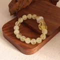 Detailed shot of yellow beaded bracelet with carved fox charm and white agate ring. - Citrine