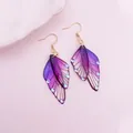 Close-up of purple gradient butterfly wing earrings with glitter and blue accents. - Rhinestone Decoration / Purple