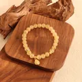 Detaillierte Ansicht des gelben Citrin-Armbands mit goldenem Anhänger auf Holz - Gold Rutilquarz Flaschenkürbis Armband
