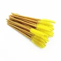 Detailed macro view of yellow disposable mascara wands with gold handles for makeup - Yellow