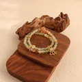 Close-up view of a natural green fluorite and citrine beaded bracelet on wooden display. - Prehnite and Yellow Quartz Double Wrap