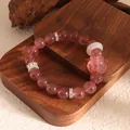 Elegant strawberry crystal beaded bracelet with nine-tailed fox charm shown on wood display - Strawberry Quartz With Accessories