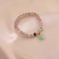 Close-up of a natural strawberry quartz bracelet with a green jade-style donut pendant on silk. - Peace Buckle and Multi-bead Style