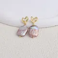 Dettaglio di eleganti orecchini a perno con perle barocche viola e cuori dorati. - Cuore / Perla Barocca Viola / Gold heart stud earrings-purple square Baroque