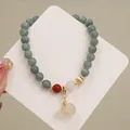 Primer plano de una pulsera de cuentas de jade con un fino colgante de piedra en forma de calabaza - Colgante de Calabaza de Calcedonia / Gris Azulado