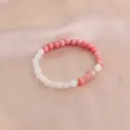 Nahaufnahme eines Armbands aus natürlichen rosa und weißen Kristallperlen auf Satin - Rosa Weiß Rosa Riss-Hauptstein Stil