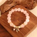 Elegantes Armband aus rosa Rosenquarzperlen mit goldenen Anhängern auf Holzständer - Jin Fen Shi Jia Stil Armband / Rosa