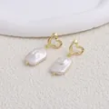 Dettaglio di orecchini a cuore dorati con perle d'acqua dolce barocche naturali - Cuore / Perla Barocca Bianca / Gold heart stud earrings-white square Baroque