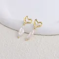 Dettaglio ravvicinato di orecchini a cuore dorati con eleganti perle barocche. - Cuore / White Bar Pearl / Gold heart stud earrings-white bar Baroque