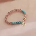 Detailed view of strawberry quartz crystal bracelet with gold Fu character charm - Blue Crystal and Fu Charm Style