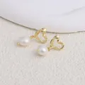 Dettaglio macro di eleganti orecchini a cuore dorati con perle naturali d'acqua dolce - Cuore / Perla Bianca Rotonda / Gold heart-shaped stud earrings-White Pearl