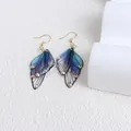 Detailed macro shot of blue-purple butterfly wing earrings with sparkling rhinestones. - Zirconia Style / Blue