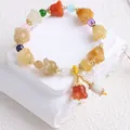 Detailansicht der bunten Jinsiyu-Steinperlen und Blumenanhänger an einem Armband. - Goldenes Seidenarmband Mit Maiglöckchenmotiv