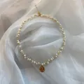 Elegant detail view of a woven natural freshwater pearl necklace with a gold coin pendant - Necklace Style / Gold