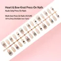 Vue détaillée de 30 faux ongles nude à presser avec motifs de nœuds et cœurs noirs - Tailles Mixtes XS/S/M / Style Cœur Nœud Rose Nude (S113-T) / Pack de 30