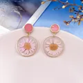 Vue détaillée de la fleur de chrysanthème rose séchée dans des boucles en résine. - Rose