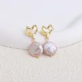 Dettaglio orecchini a cuore dorati con perle barocche rosa su sfondo bianco pulito - Cuore / Purple Flat Round Pearl / Gold heart stud earrings-purple Flat Baroque