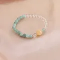 Nahaufnahme eines Naturkristall-Armbands mit grünen Achat- und klaren Quarzperlen. - Hellgrüner Achat Weißer Kristall Gelbe Große Perle Stil