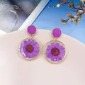 Vue détaillée des boucles d'oreilles marguerites séchées violettes en résine - Violet