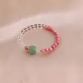 Detailaufnahme eines Kristallarmbands mit rosa Perlen und grünem Achat auf Seide - Rosa Rhodochrosit Weißer Kristall Grüner Kürbis Achat Stil